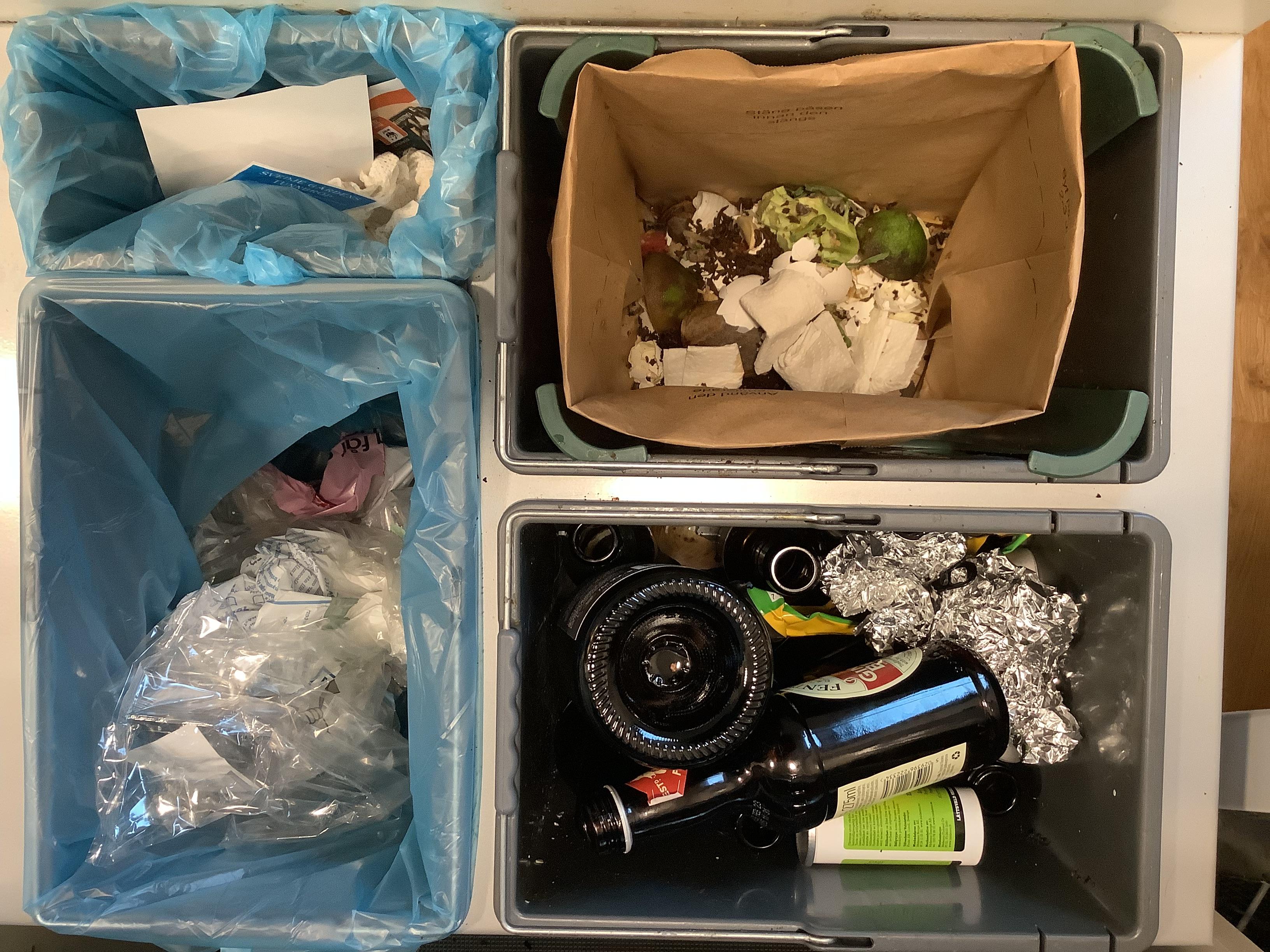 Bilden visar fyra sorteringskärl under en diskbänk. En för restavfall, en för matavfall, en för plast och en för glas och metall.