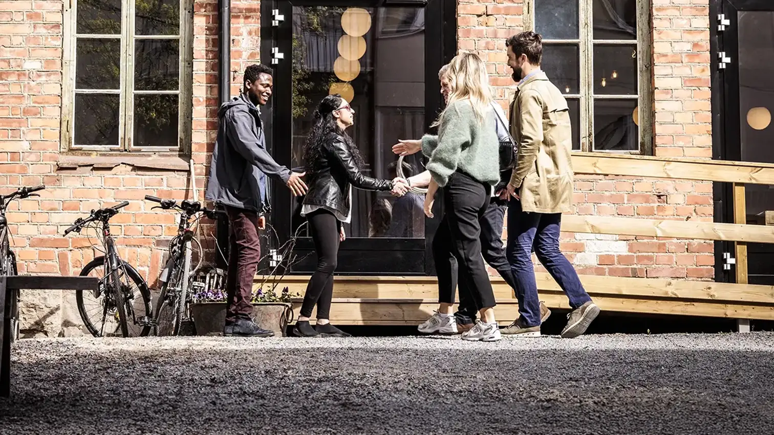 Ett gäng vänner som hälsar på varandra framför en port