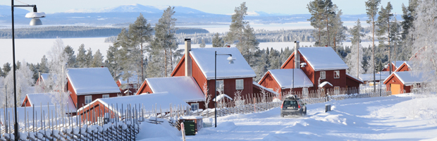 Bild på tre röda bostadshus i vinterlandskap.