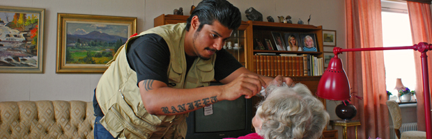 Bild på yngre man som ger ögondroppar till äldre kvinna.