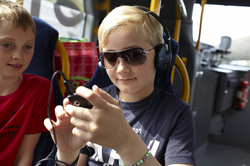 Två pojkar sitter på buss och tittar på telefon