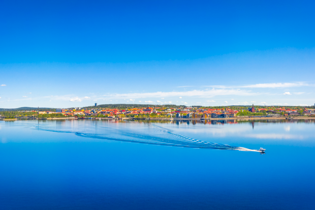 Bild på Storsjön med vy över Östersund. En båt åker över den blanka vattenytan.