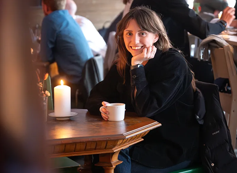 Kvinna sitter i cafemiljö vid ett bord med ljus
