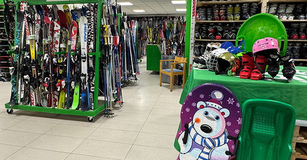 En butik där hyllorna är fyllda med skidor, pjäxor och pulkor