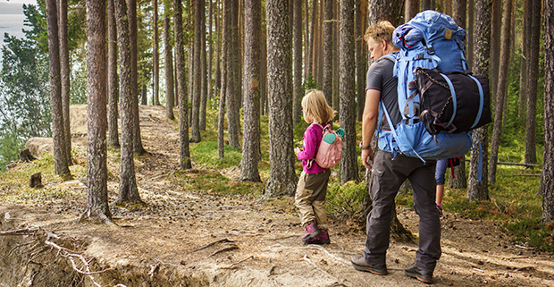 Två vandrare en vuxen och ett barn går på en stig i skogen