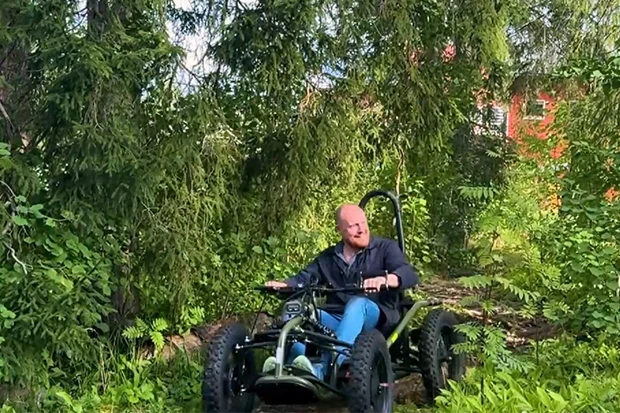 Bild på Niklas Daoson som kör en terrängrullstol i skogen.