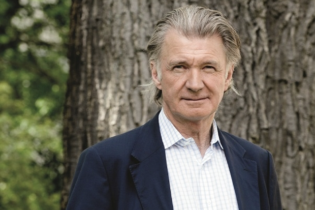 Proper äldre man med grått hår i backslick tittar in i kameran med vänlig och vaken blick.