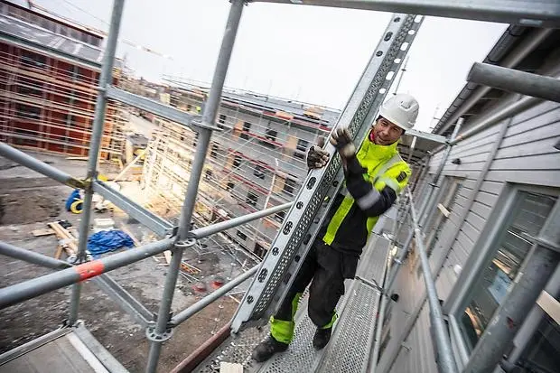 Byggarbetare högt uppe på byggställning
