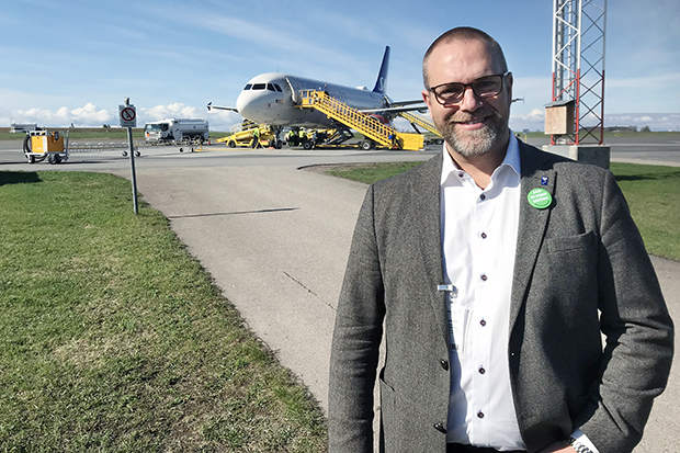 Anders Wennerberg står och tittar mot kameran, i bakgrunden syns ett flygplan som tankas.
