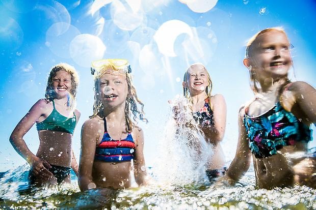 Glada tjejer som badar i en sjö en solig dag