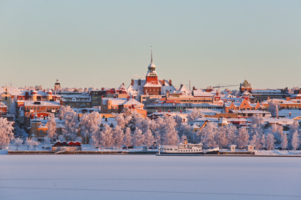 Isbelagd Storsjön i förgrunden med ett vintrigt Östersund i bakgrunden. Rådhuset sticker upp bland de snötäckta taken.