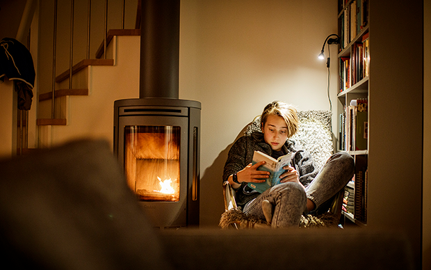 Barn som läser intill en kamin där elden sprakar.