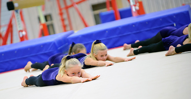 Gymnastiktjejer gör övning på matta