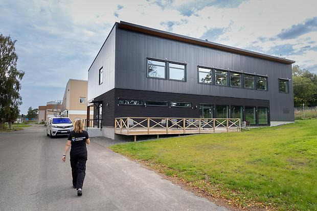 En människa går bort mot ett stort grått hus, det nya labbet.