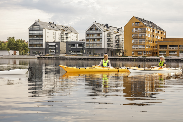 Två personer paddlar på Storsjön. I bakgrunden syns Storsjö Strand med de nya bostadshusen.