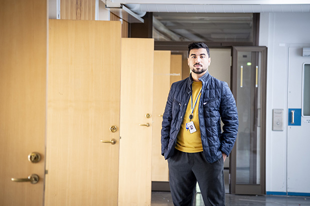 Muaz står i en korridor med flera öppna dörrar bakom sig.