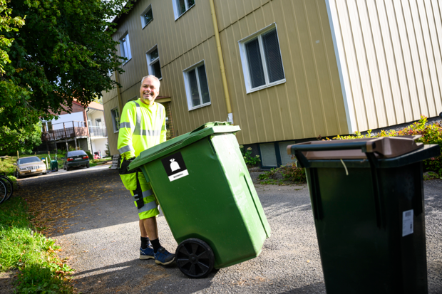 Sopbilschaufför som drar ett avfallskärl 