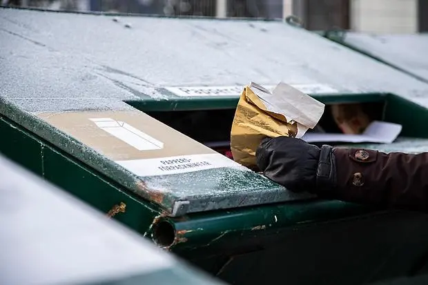Person som slänger julklappspapper i container