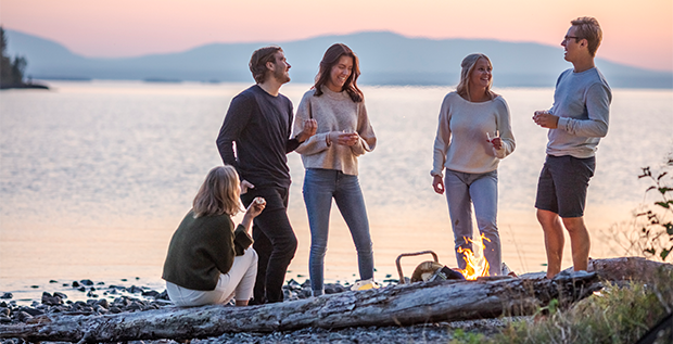 Ett gäng personer står i solnedgång vid en strand