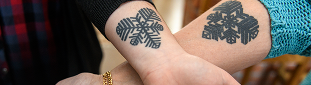 Två underarmar i kors med tatueringar i form av Östersundshjärtat