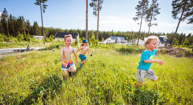Barn som springer i gräset framför nybyggda villor