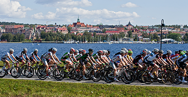 Klunga av cykelåkare i förgrunden. Östersund och Storsjön i bakgrunden