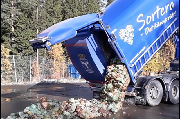 Sopbil som tömmer ut matavfall på marken. Skåpet är upprest och bakluckan öppen.
