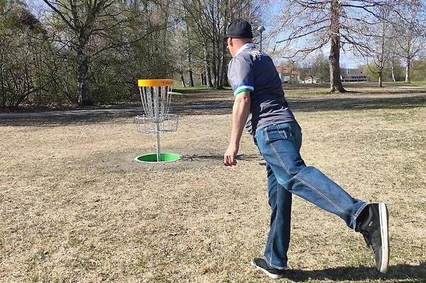 En person som spelar discgolf i en park. 
