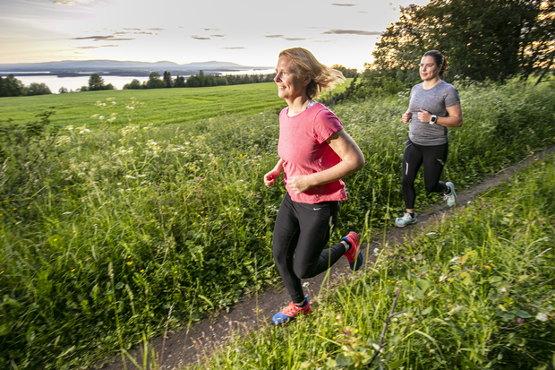 Två tjejer springer på stig med vacker utsikt