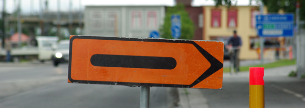 Gatumiljö med uppställd vägskylt som anger tillfällig omledning av trafiken