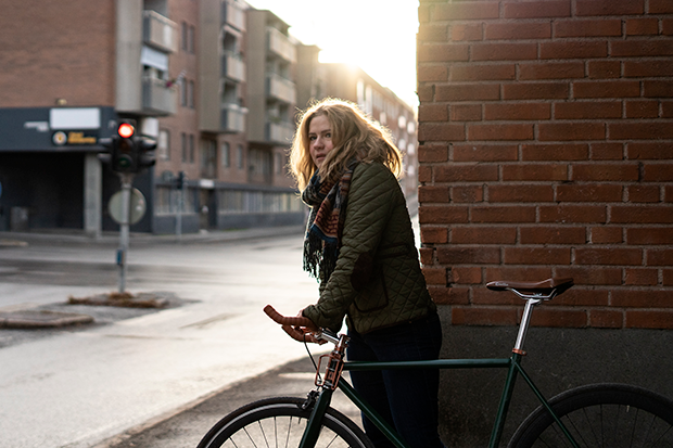 Ung kvinna som leder en cykel i gatumiljö