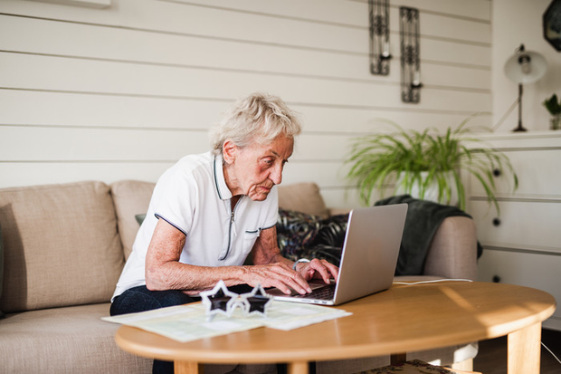 Äldre man som sitter och skriver vid dator
