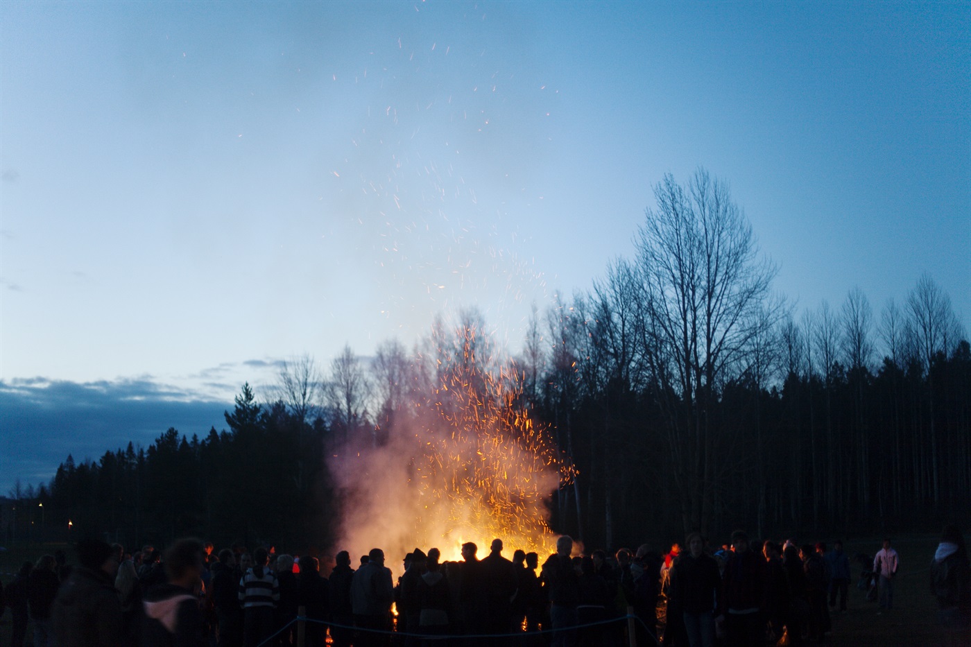 En grupp människor runt en majbrasa.
