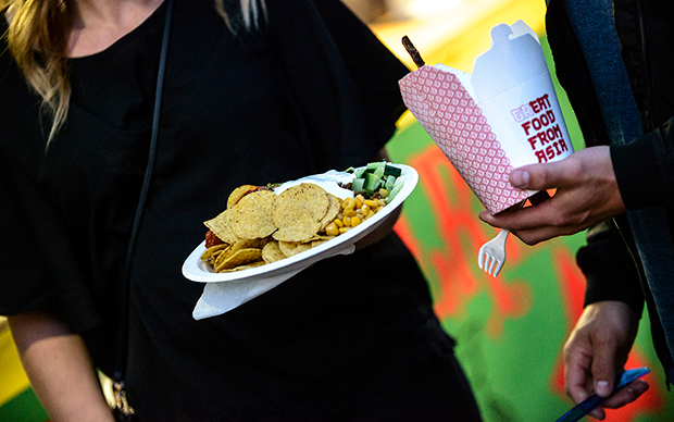 Kvinna som håller i en papperstallrik med taco-chips. En annan person håller i en papperförpackning