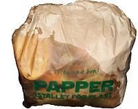 Brun papperspåse med stor blöt fläck. Man kan ana apelsinskal inne i påse. Påsen har texten "Titta vad bra! Papper istället för plast"
