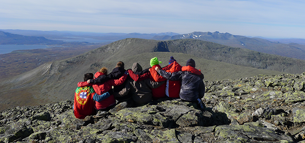 Ett gäng sitter på en bergstopp och håller om varandra