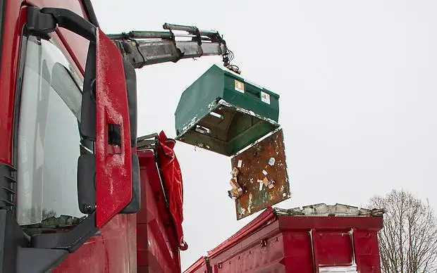 Lastbilskran som lyfter container, botten på containern är öppen.