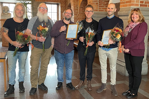 Fem pristagare med diplom och blommor i famnen.