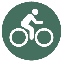 Rund mörkgrön skylt med piktogram för cykling.