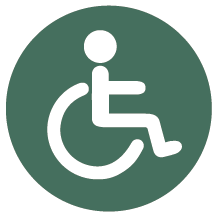 Rund mörkgrön skylt med piktogram för funktionshindrad.