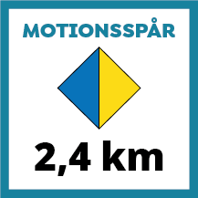 Skylt för motionsspår på 2,4 km med tvåfärgad romb i blått och gult. Färgerna indikerar dels längden på spåret samt att spåret har belysning.