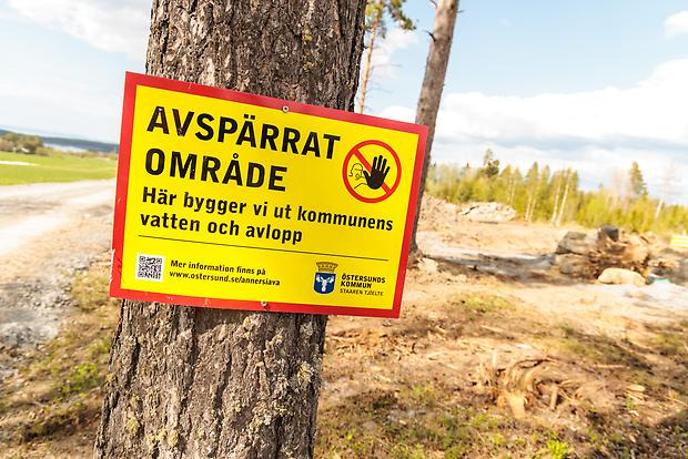 En skylt med texten "avspärrat område" sitter på en tallstam