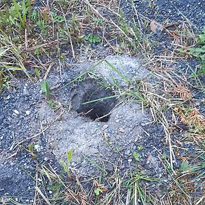 Ett borrhål o marken, grått borrkax-sand