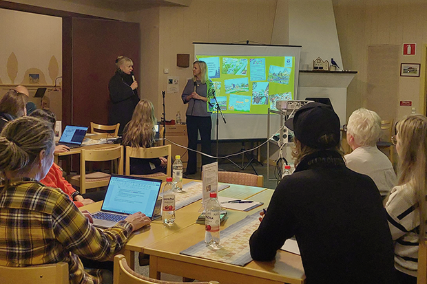 Personer deltar i möte med presentation på projektorduk i ett konferensrum.