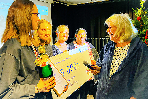 Fyra kvinnor håller upp en överdimensionerad check.