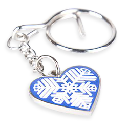 Nyckelring i metall formad som ett hjärta, med ett vitt Östersundshjärta tryckt ovanpå en blå bakgrund.