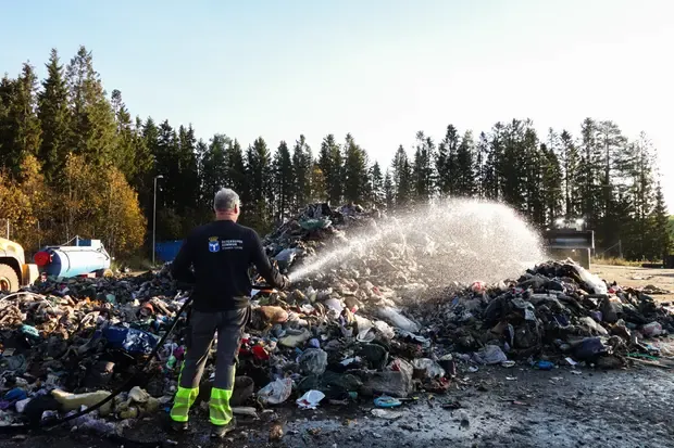 Man sprutar vatten på sophög som brunnit