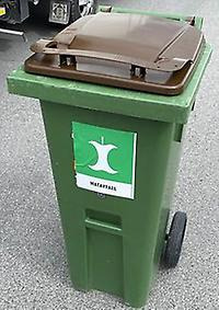 Grön tunna med brunt lock, märkt med en äppelskrutt som symbol för matavfall.