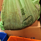 Grön påse med texten biobag på. Påsen är fylld med kaffesump.
