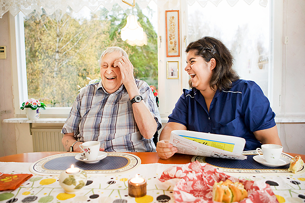 Fika och skratt med äldre man och kvinna i personalen.